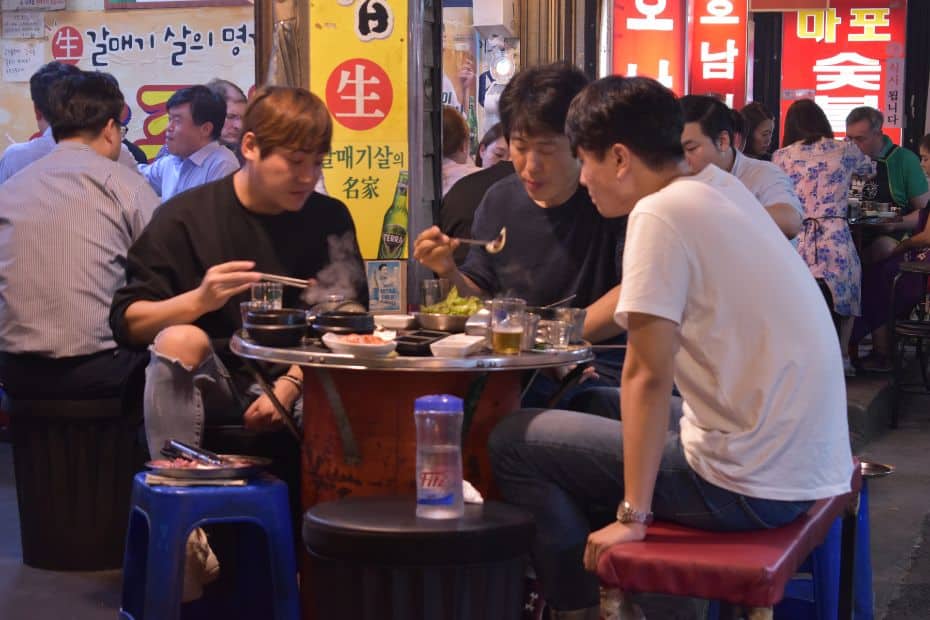 Complete South Korea Travel Guide 2024: Korean Travel Tips 112 People eating a Korean BBQ meal on the street