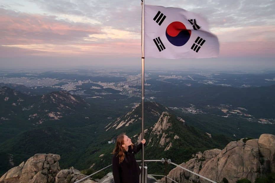 How To Hike Bukhansan Baegundae Peak: Seoul's Best Hike 2024 43 Person holding Korean flag on Baegundae Peak