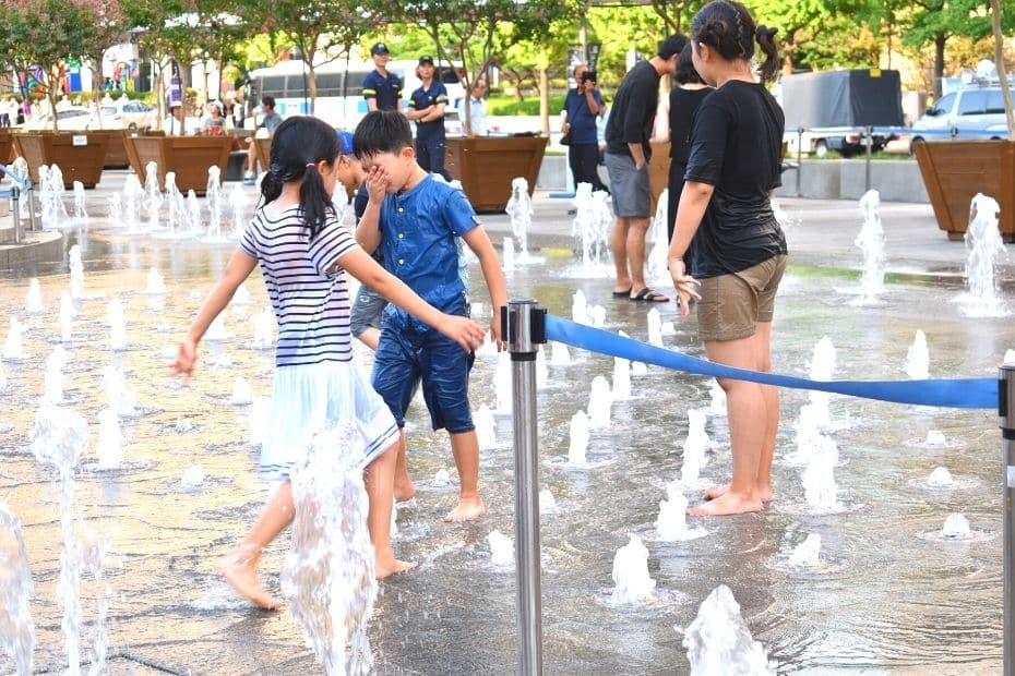 How To Survive Summer In Seoul 2024: 10 Tips To Stay Cool 15 Children in Seoul in summer playing in the water at Cheonggye Plaza