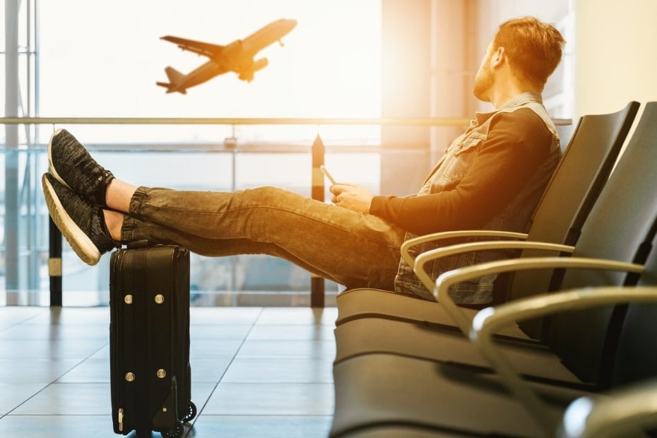 Flying To Korea: How To Get Cheap Flights To Korea In 2024 15 Man relaxing at an airport watching a plane depart